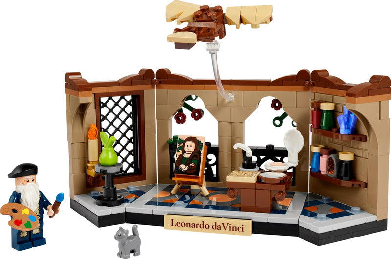 A LEGO Leonardo da Vinci minifigure plays in a painted studio scene with Leonardo seated at a desk, paint palette